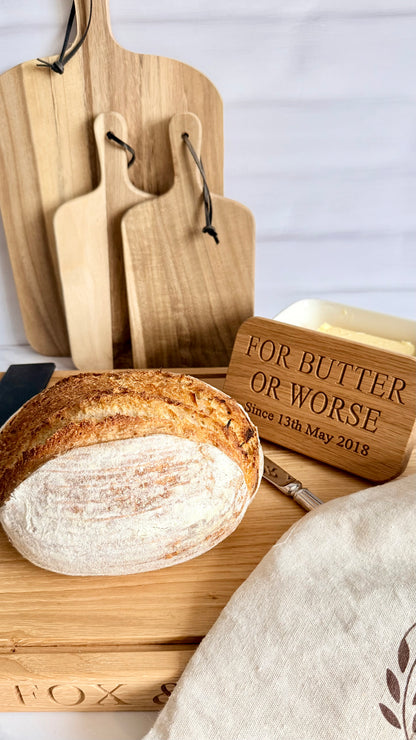 Wooden cutting boards and a loaf of bread on a white surface with a decorative wooden block.