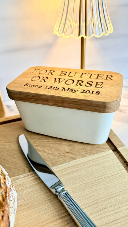 Butter dish with wooden lid and engraved text on a wooden surface with a knife.