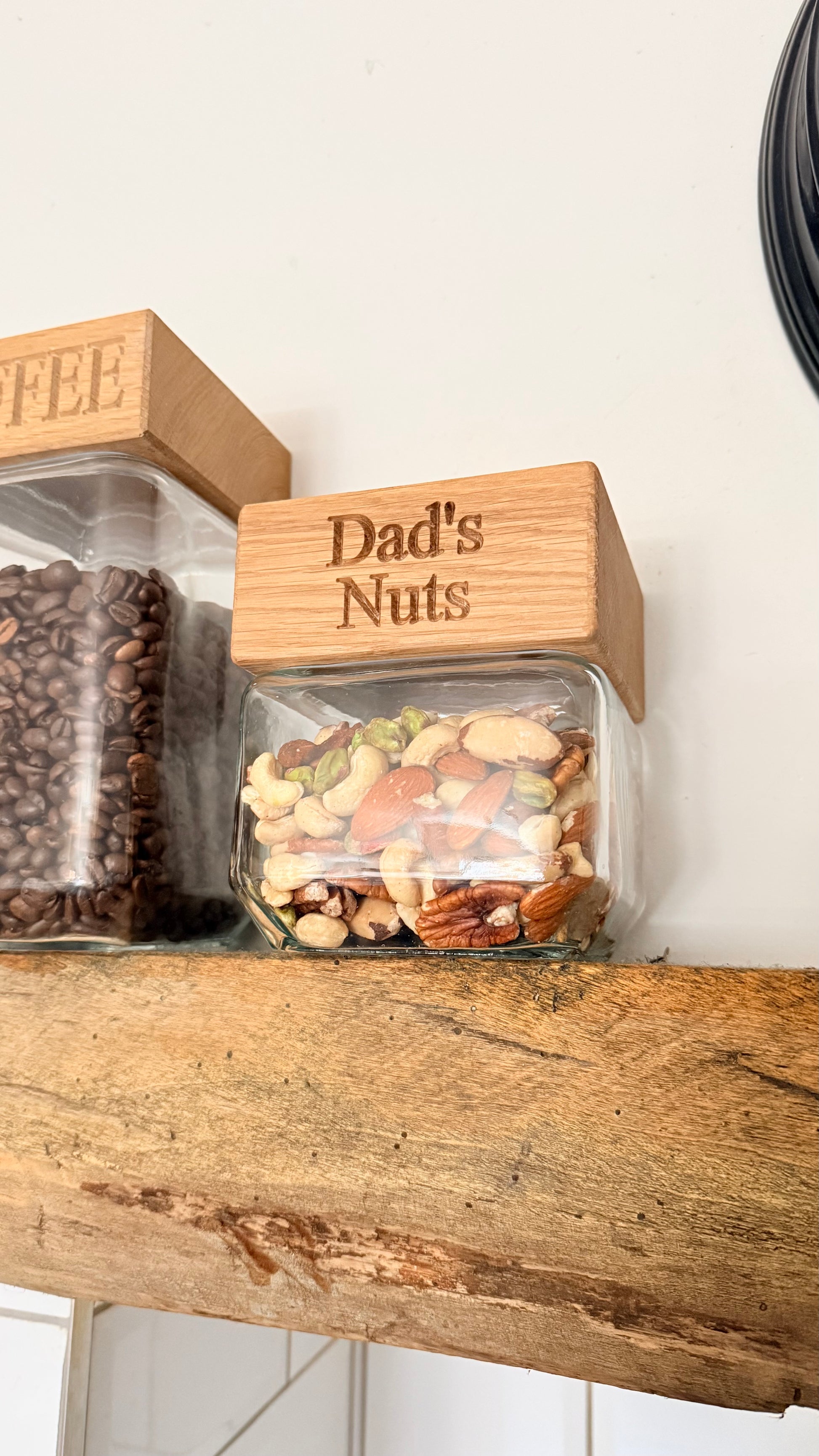 Jar labeled 'Dad's Nuts' on a wooden shelf with another jar labeled 'Coffee'.