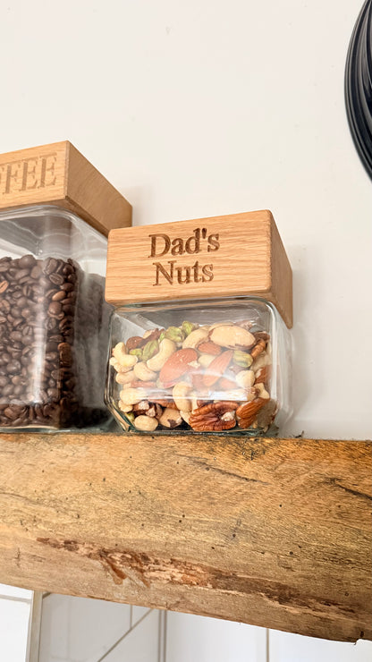 Jar labeled 'Dad's Nuts' on a wooden shelf with another jar labeled 'Coffee'.