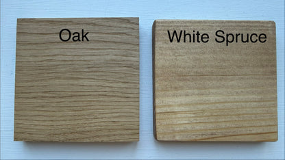 Two square wood samples labeled 'Oak' and 'White Spruce' on a light background, showing different wood grain textures and colors.